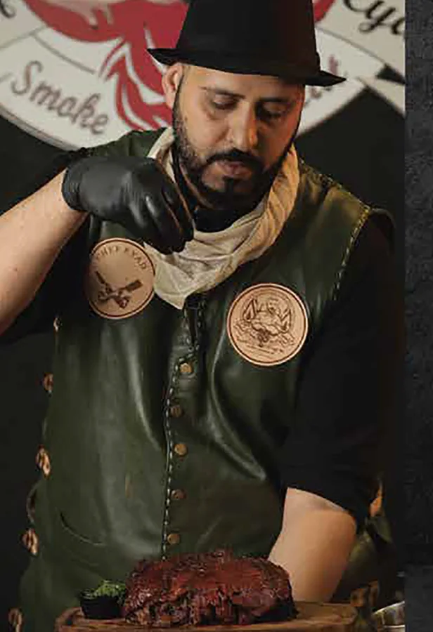 Chef Eyad Abu Alhasan seasoning a brisket at the smoker